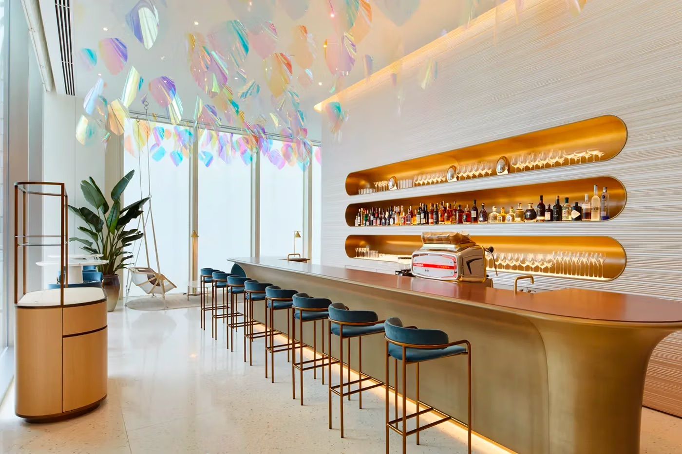 The bar area of Louis Vuitton's Le Café V features a striking design with curved brass shelving displaying spirits and glassware (Photo: Louis Vuitton)