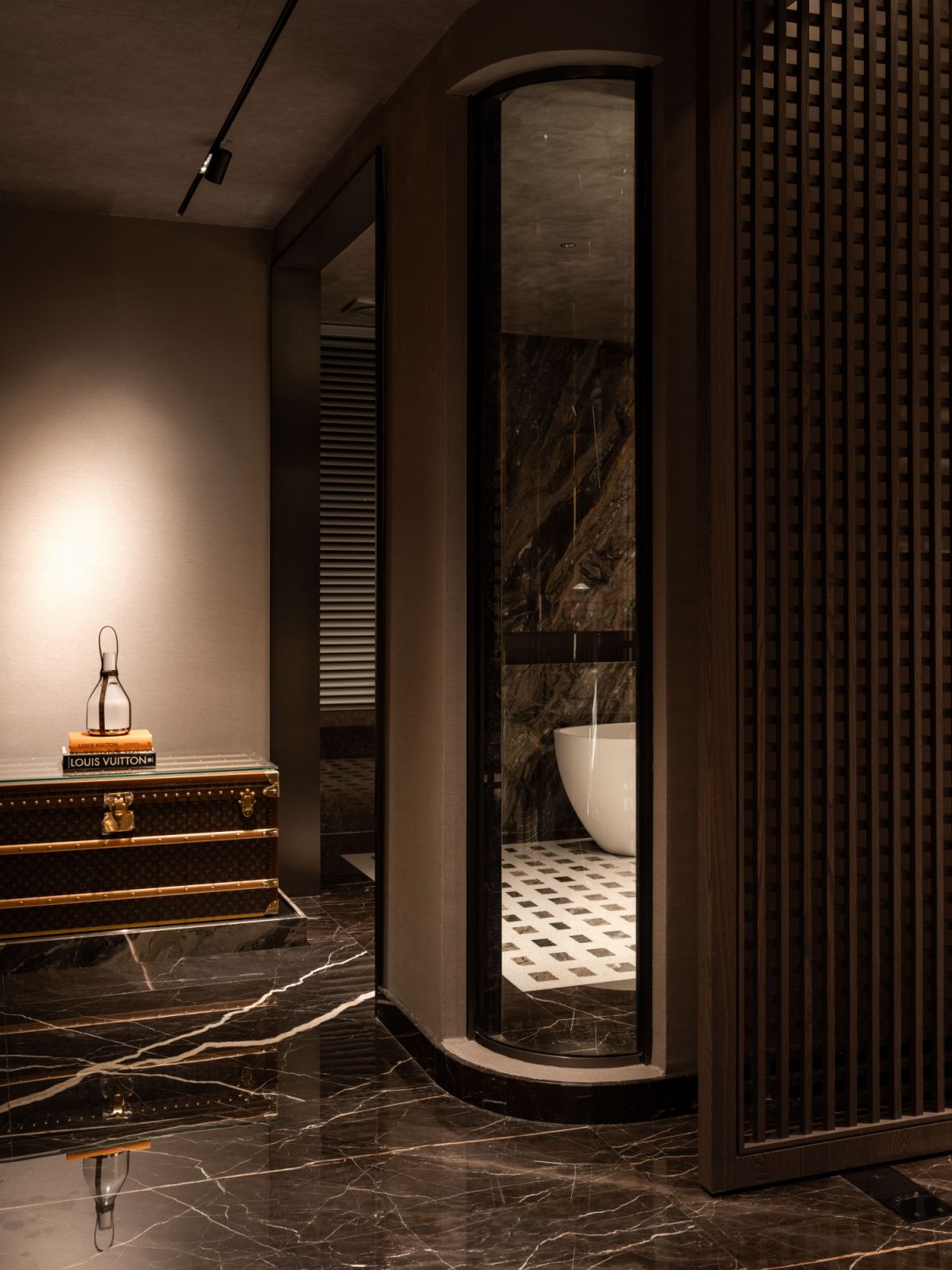 The Louis Vuitton trunk contrasts with the sleek bathtub visible beyond