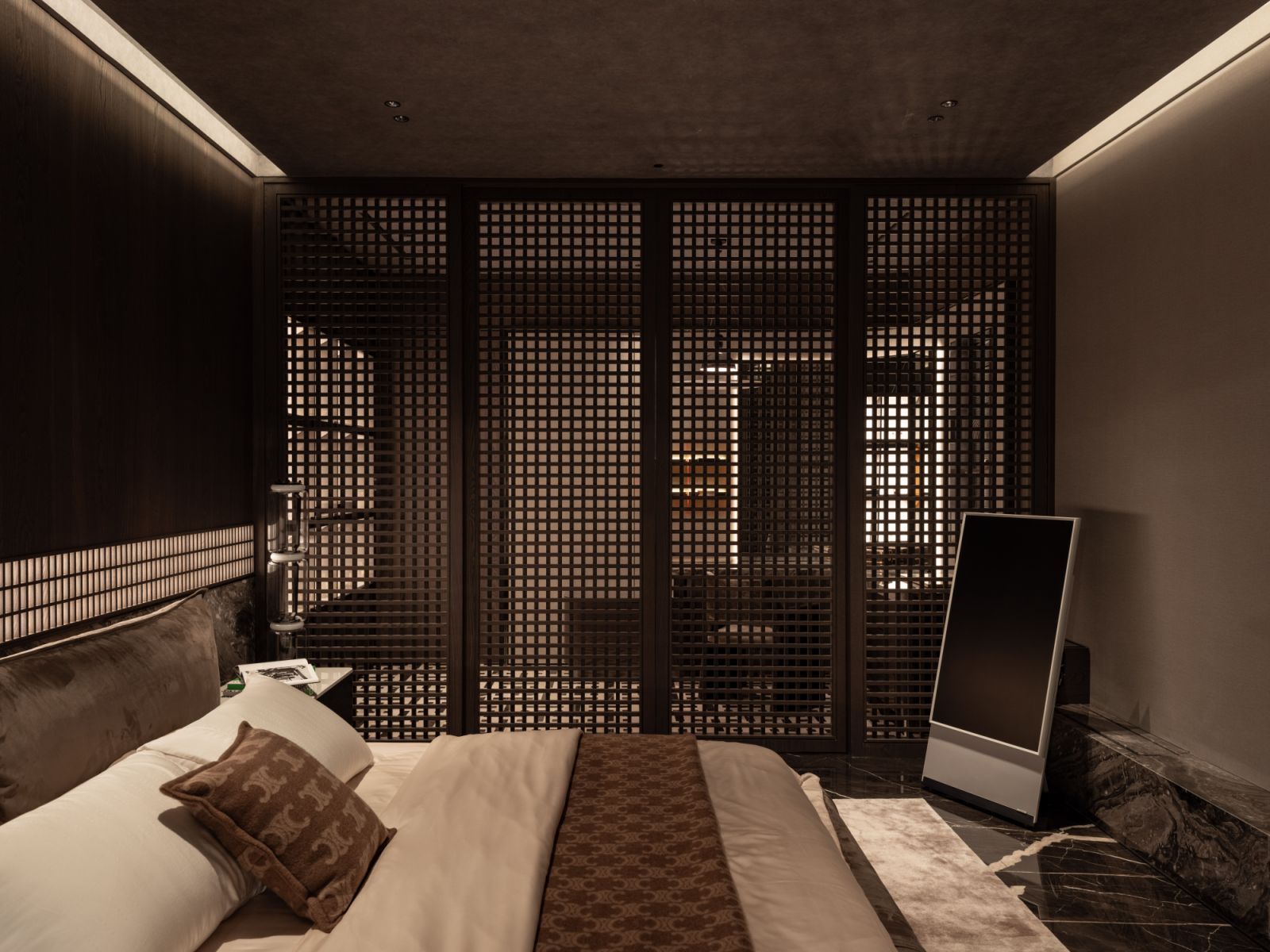The bedroom features a strategically placed architectural screen that filters light without sacrificing spatial flow.