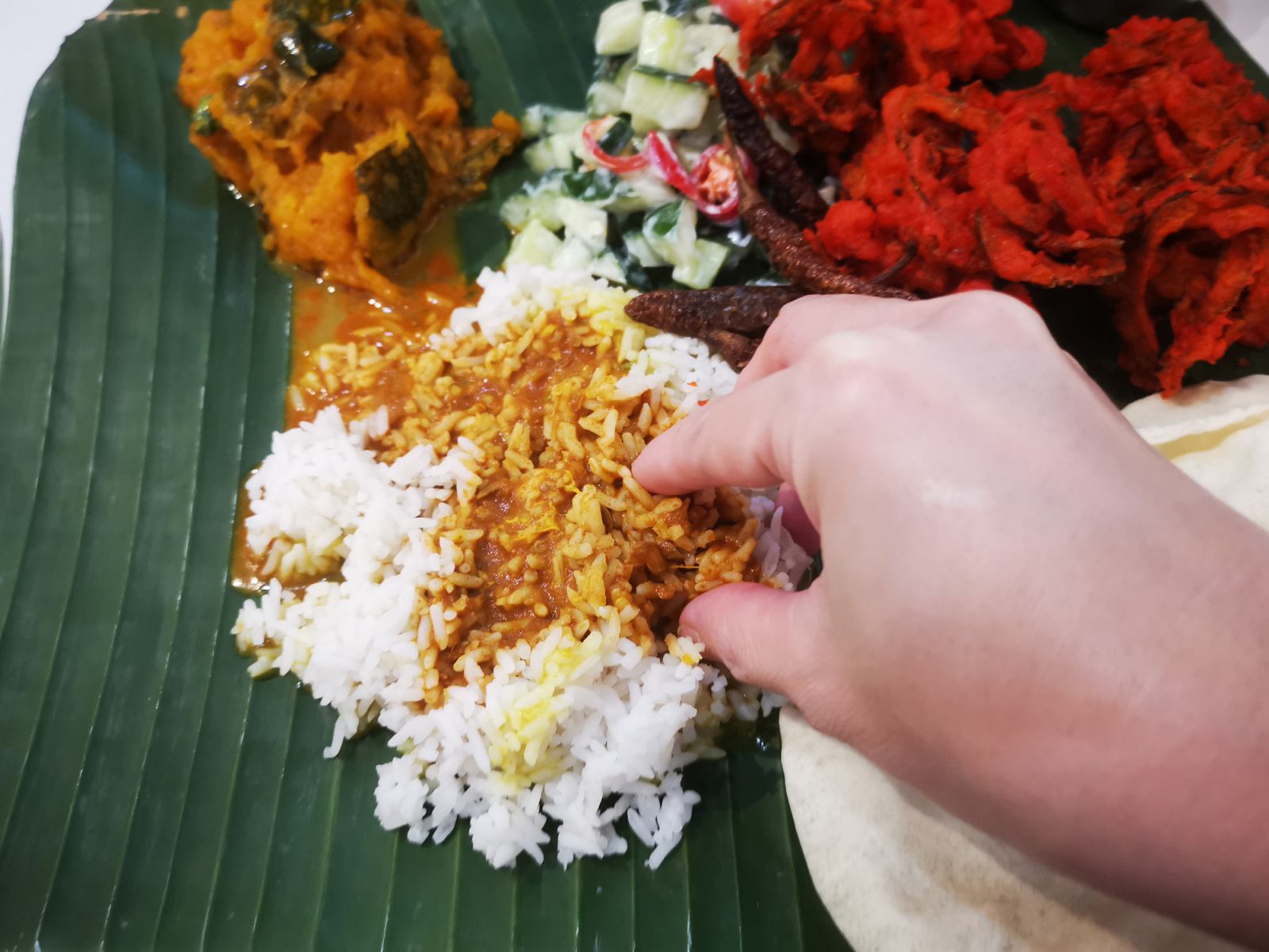Traditional banana leaf rice (curry on rice with pumpkin, cucumber, deep fried snakegourd, pappadom and rasam).
Malaysian culture is to eat with clean bare right hand instead of using cutleries.