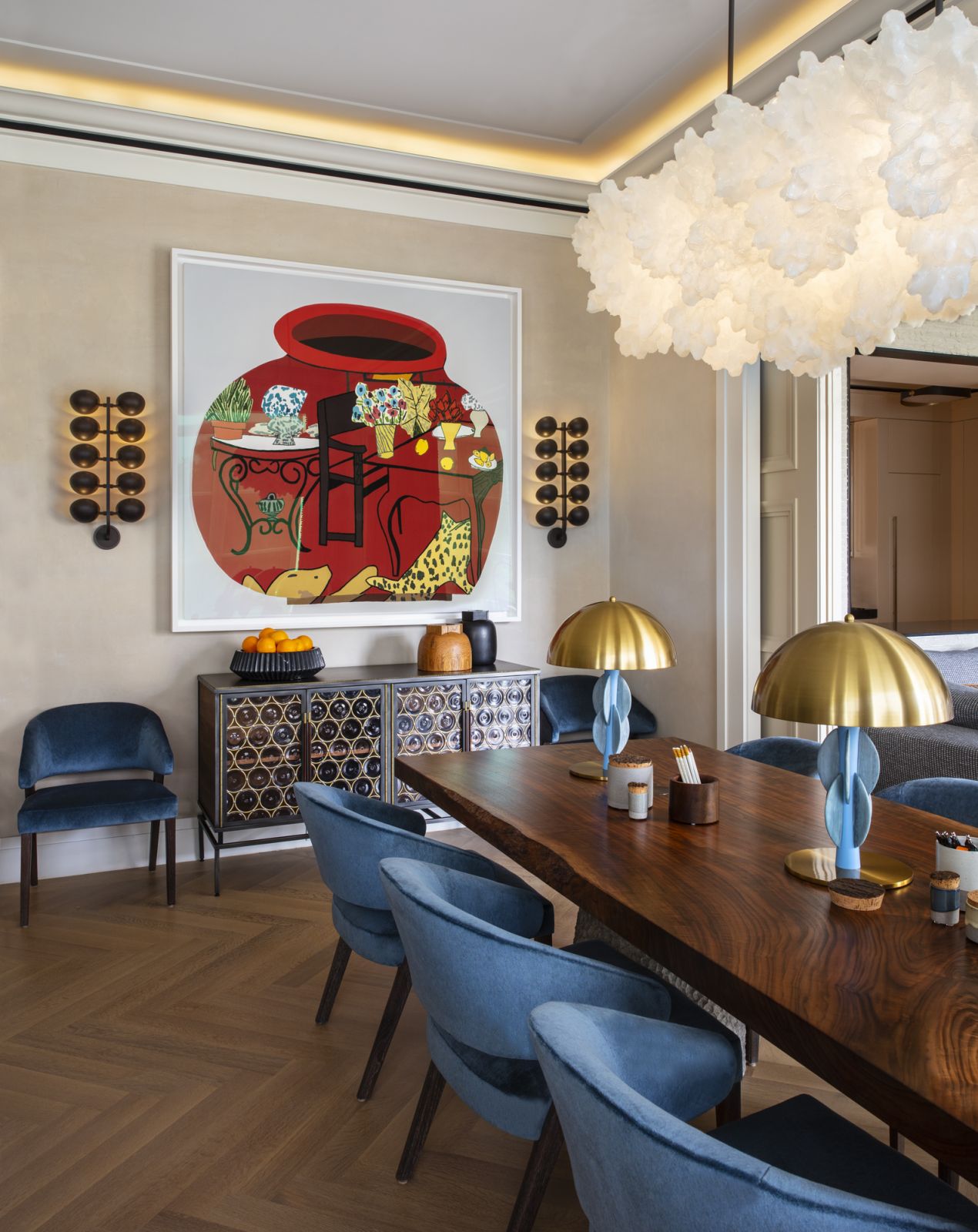 The dining room with a walnut dining table (bases by Stone Yard, top by Newell Design), a custom chandelier called “Soma Series: Duet” by Ayala Serfaty via Maison Gerard, sconces by Jonathan Browning, and the artwork “Red Still Life Pot" by Jonas Wood in a Central Park, New York family home