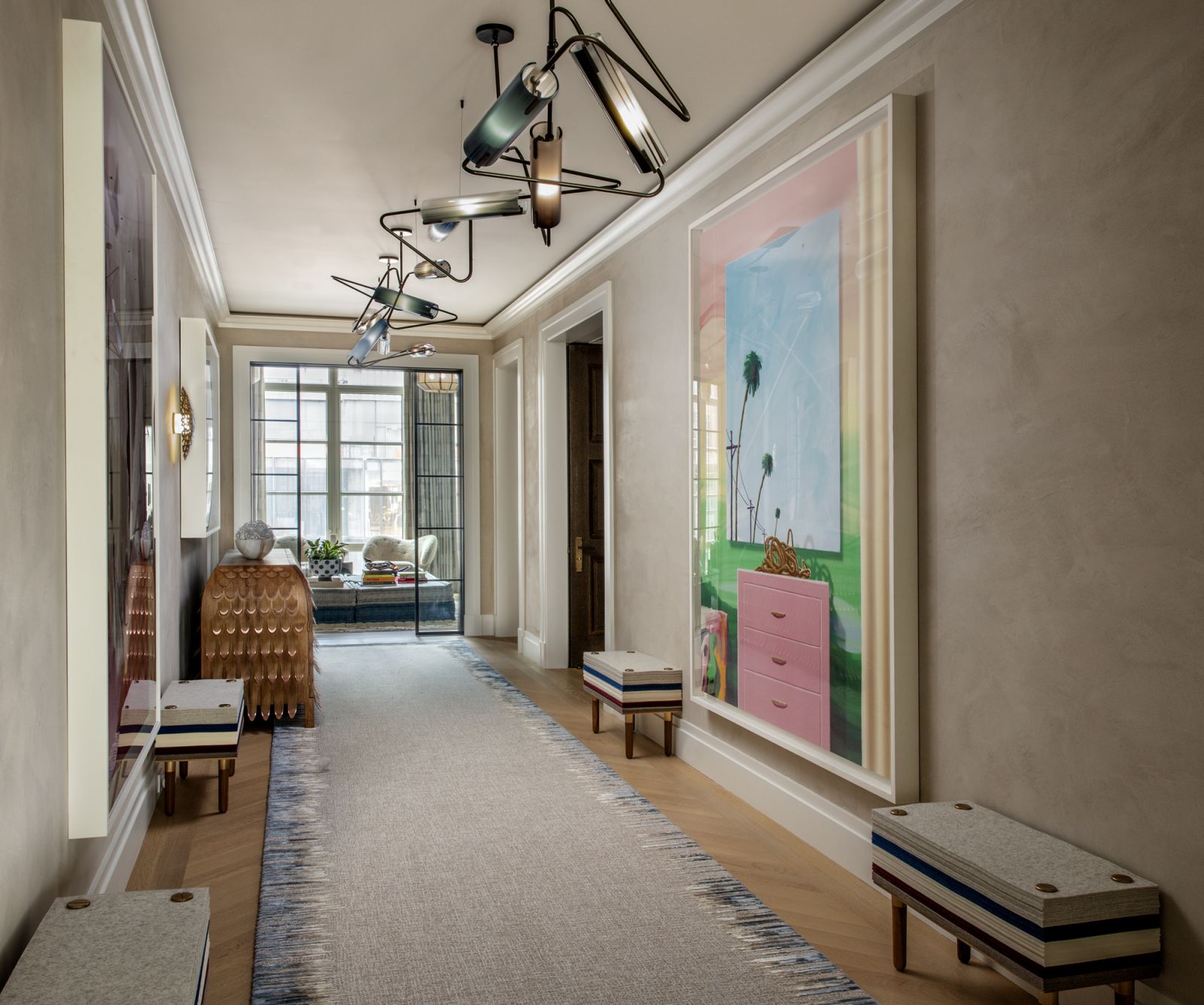 The gallery in the entryway of the home, with the artwork “Palms and Planes” by Urs Fischer beneath a chandelier by Avram Rusu Studio