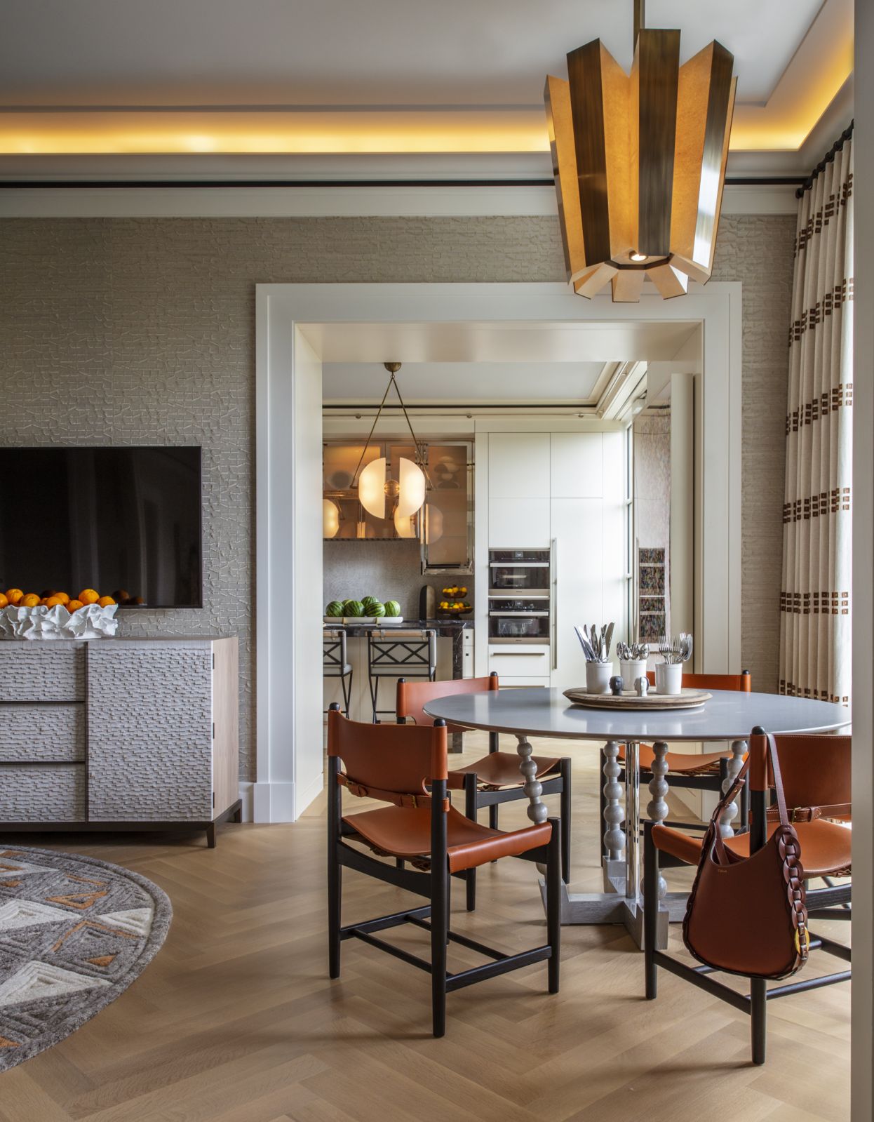 The breakfast nook in a Central Park, New York family home with a table custom table by ADJJ with a Caesarstone top, a bronze & parchment Chandelier by Laura Meroni via Carlyle Collective, and breakfast Chairs by Børge Mogensen for Fredericia via FAIR Design