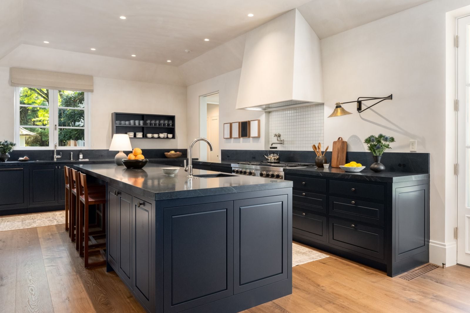 The open-concept kitchen area with dark, custom cabinetry and warm oak flooring