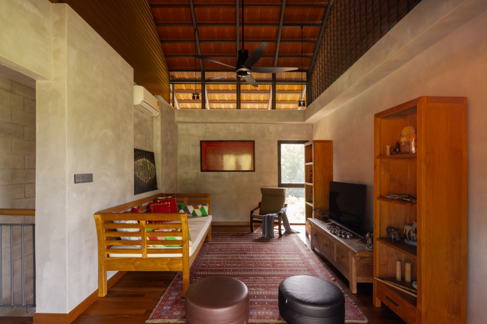The family room features exposed terracotta roof tiles and steel structure overhead, embodying the home’s raw aesthetic approach