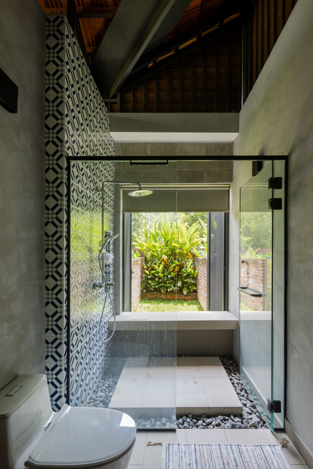 The bathroom continues the indoor-outdoor concept with a glass-enclosed shower that looks directly onto a private garden