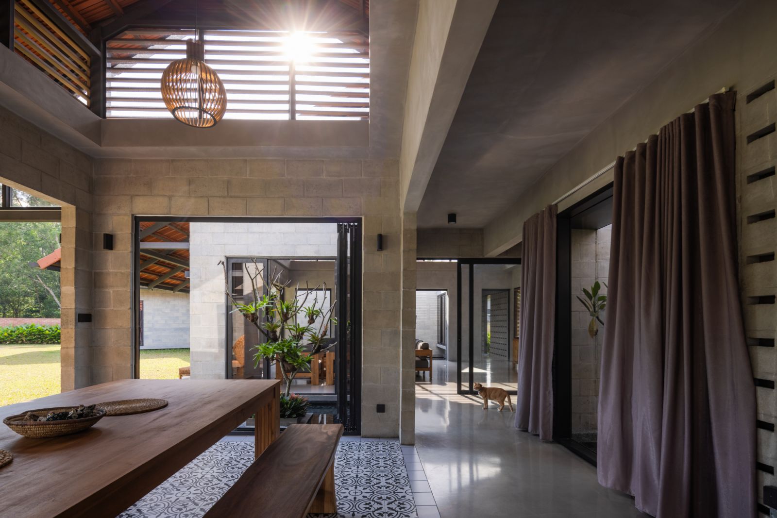 Full-height folding doors open to a courtyard with a reflecting pool, while ventilated gable ends allow sunlight to stream through slatted openings
