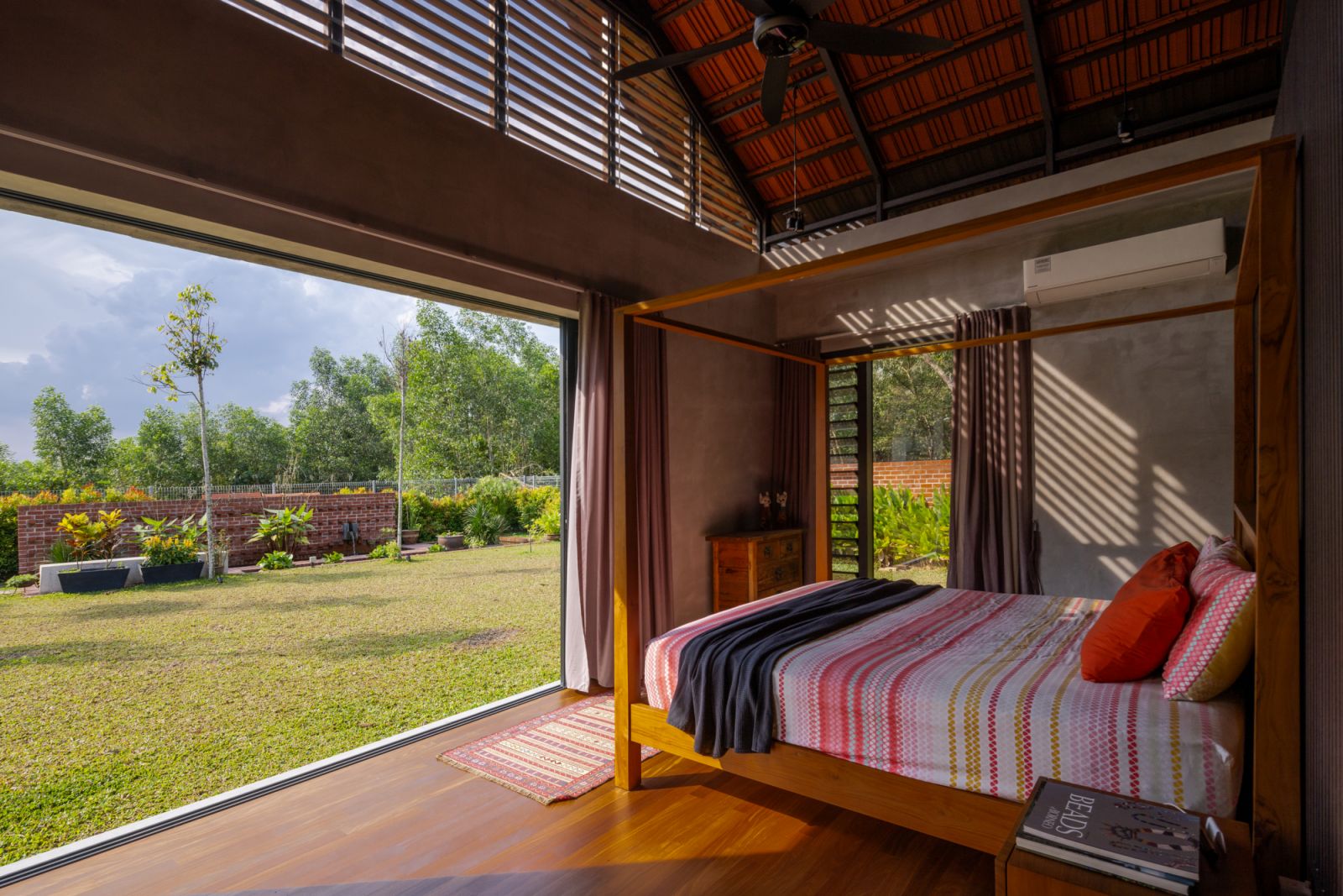 A master bedroom that opens entirely to the garden through full-height sliding glass doors, eliminating the boundary between interior and landscape