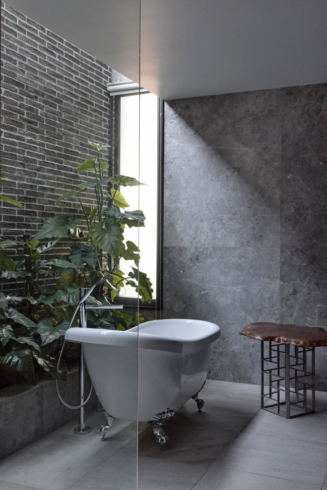 The bathroom features a freestanding tub as well as greenery and plenty of natural light