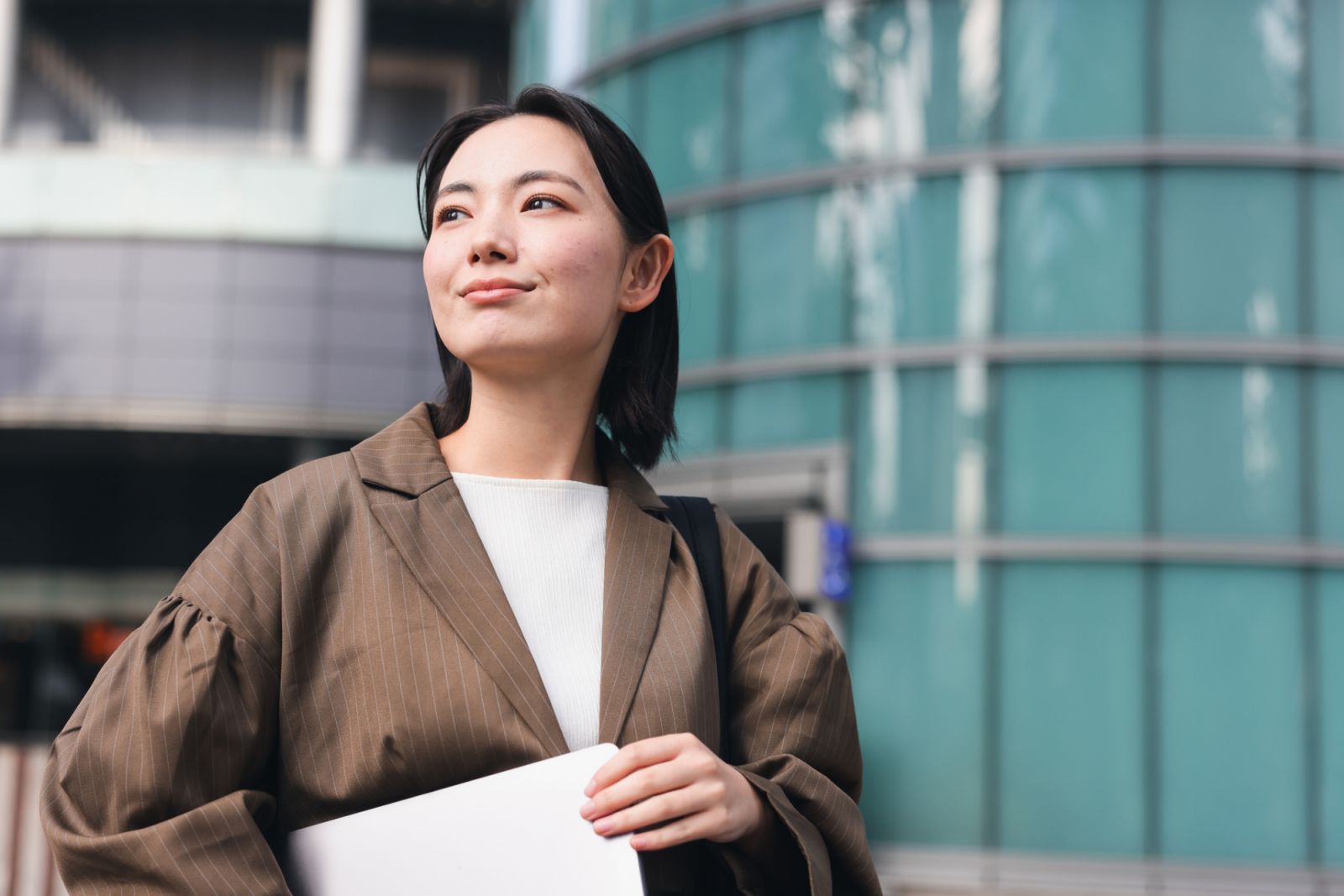 Asian Business Woman looking away camera In Outdoors,  Young woman on her morning commute.
Woman heading to work happily with a cheerful expression on her face.