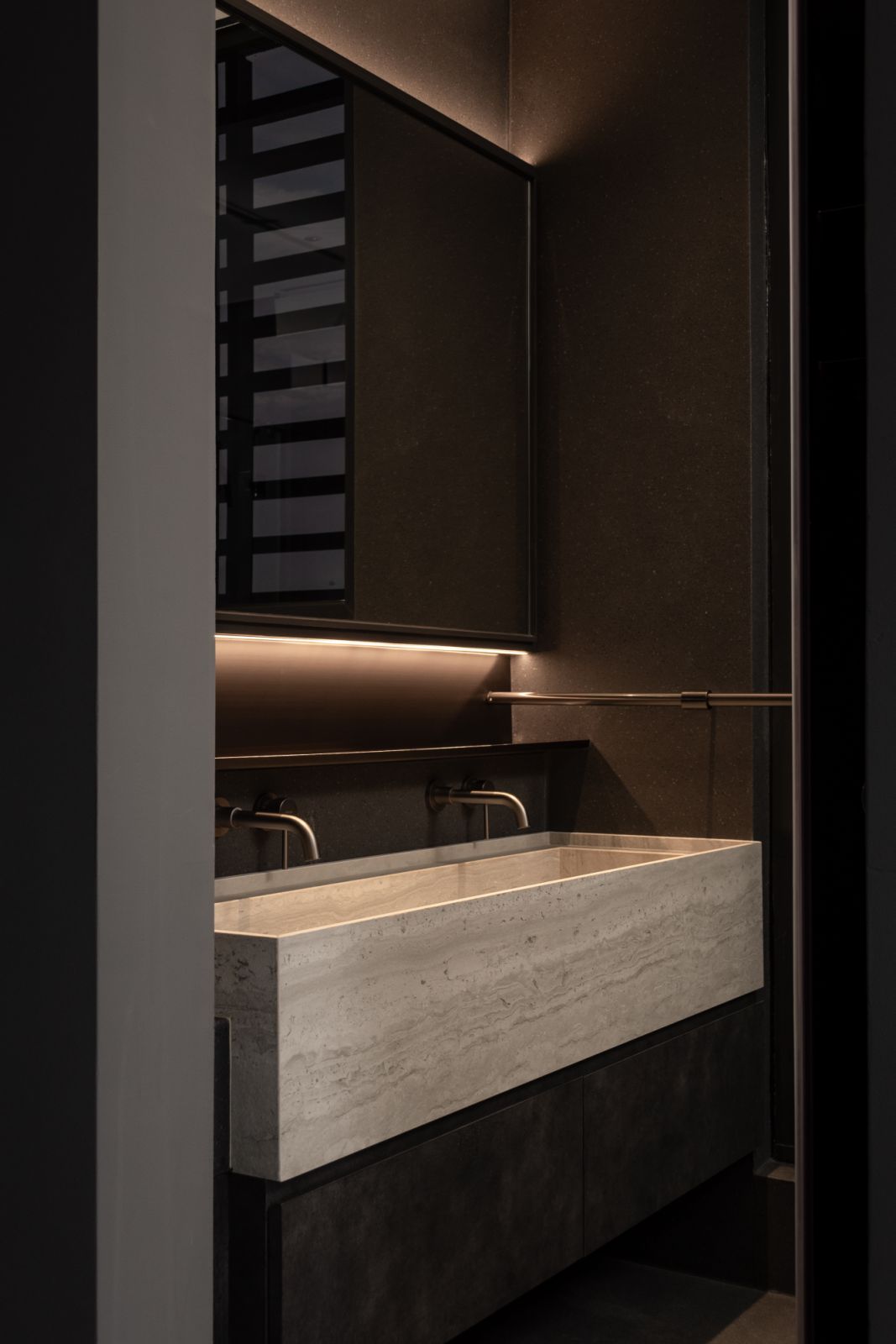 The deceptively minimal custom basin in beige engineered stone conceals complex engineering