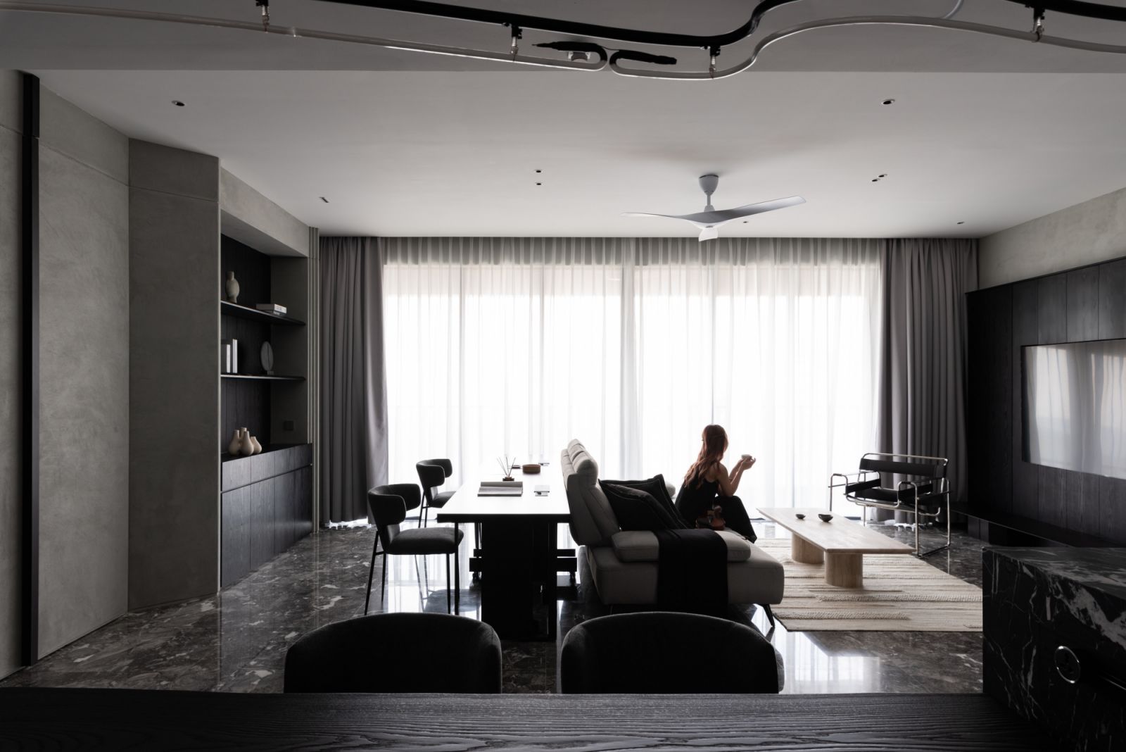 Layered ceiling treatments and strategically placed dark elements create a sophisticated nocturnal atmosphere in the living space