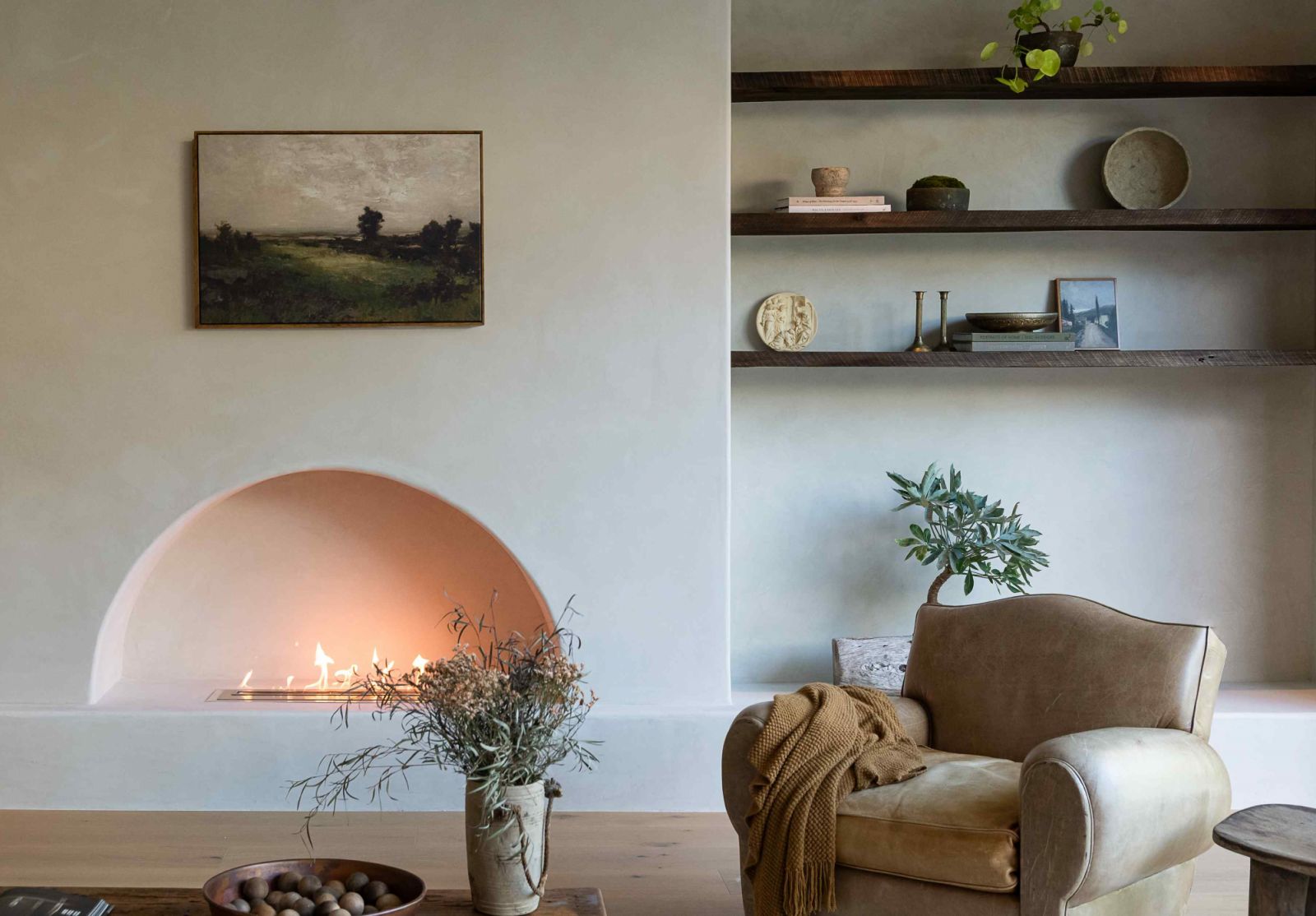 An arch-shaped fireplace flanked by niched wooden shelving