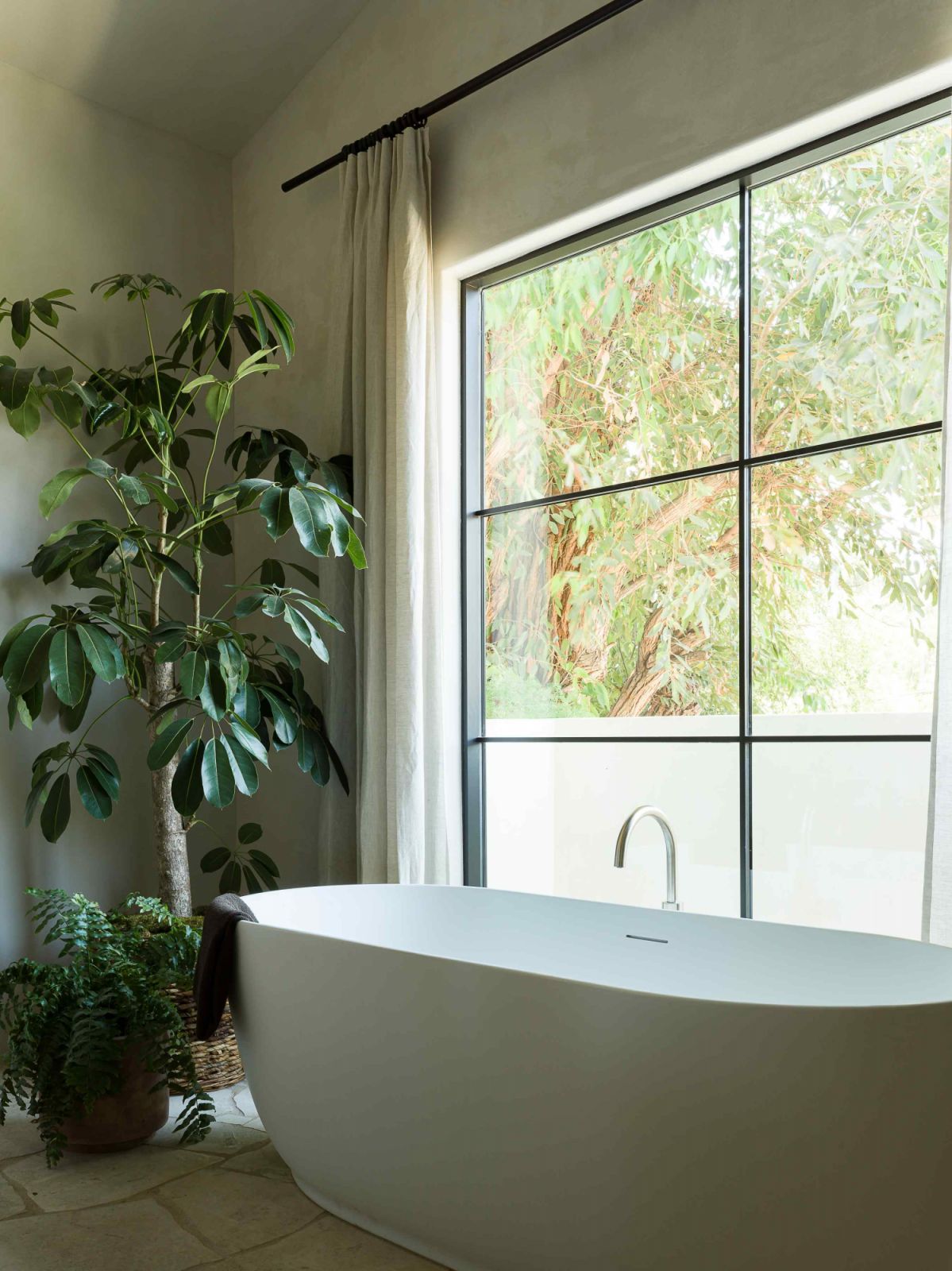 The light-filled bathroom is afforded verdant views of the surrounding greenery