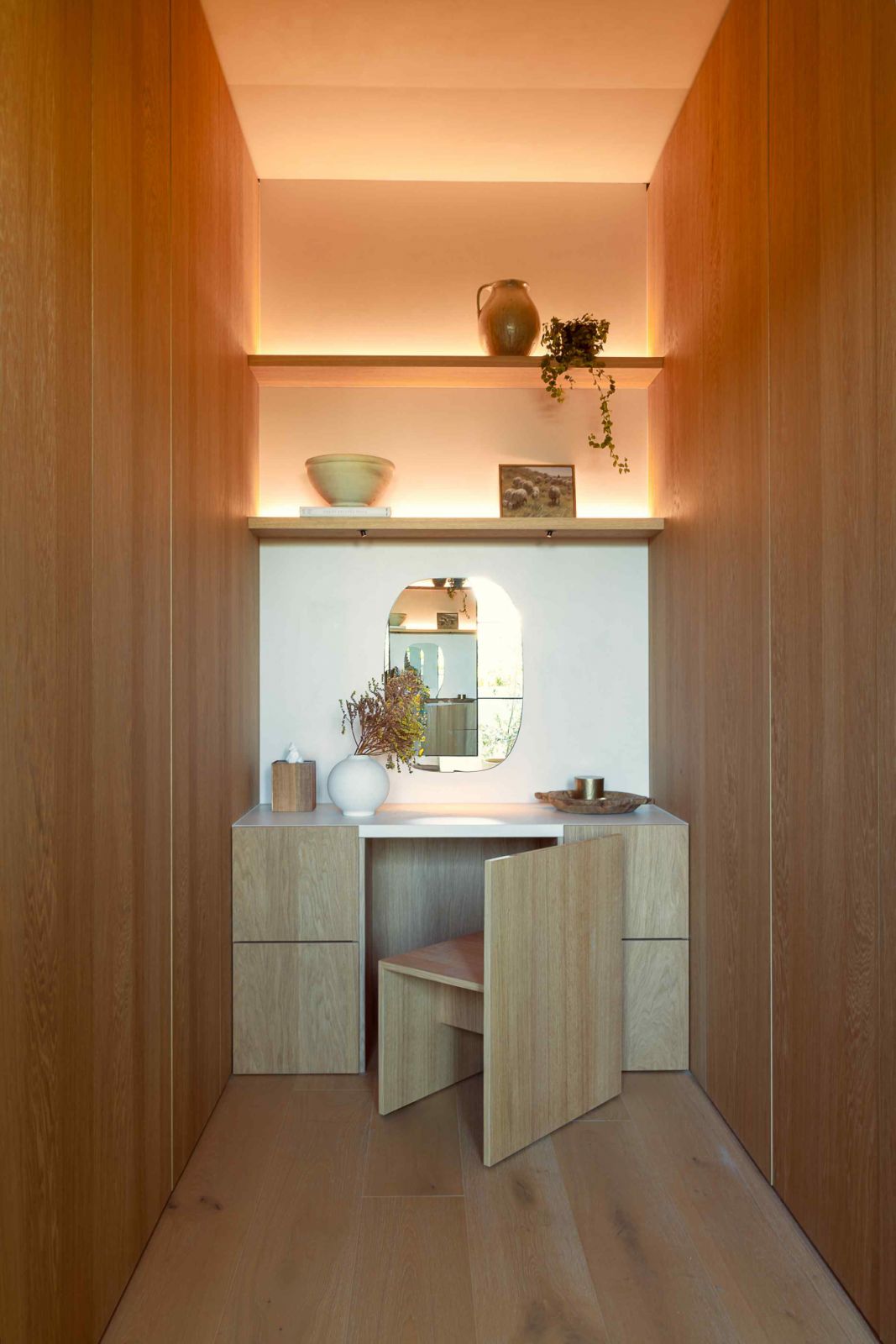 The hidden vanity and wardrobe area with warm wooden furnishing