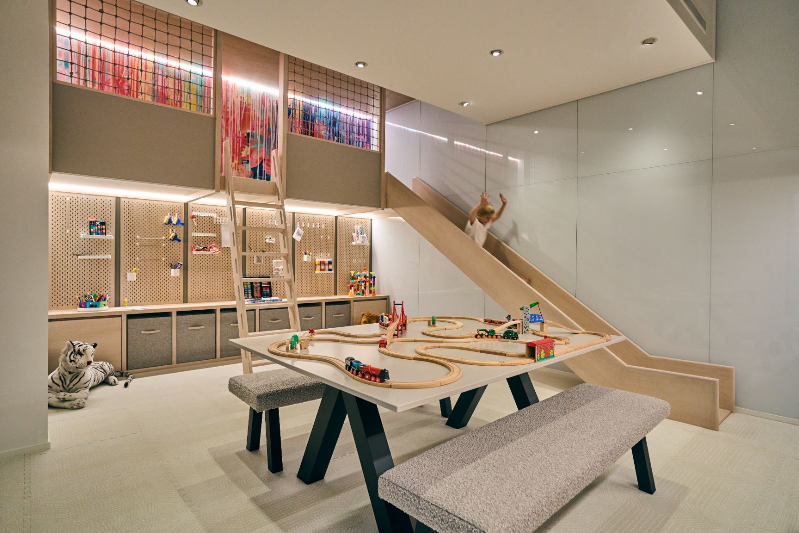 A view of the townhouse’s playroom, featuring bespoke paint splattered wallpaper, a slide and floor to ceiling storage