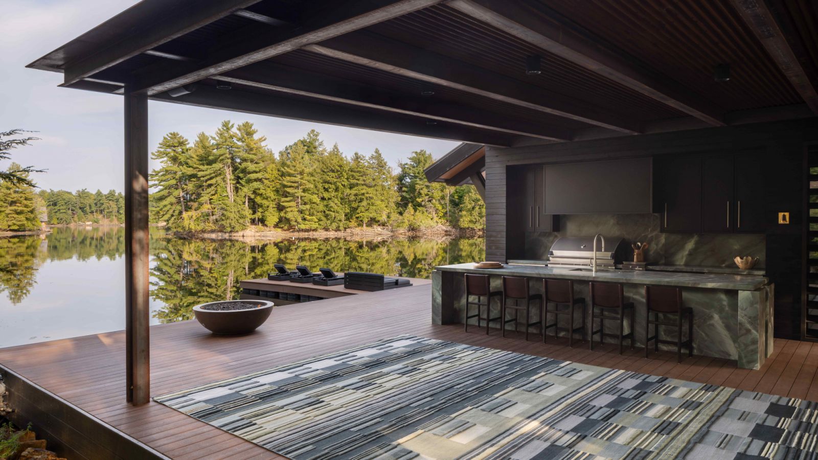 The outdoor kitchen opens into the picturesque lakefront setting in the backyard