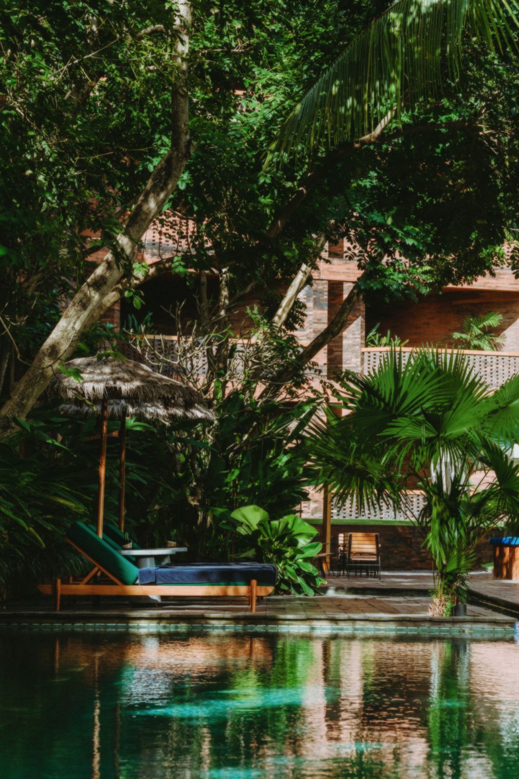 Katamama’s poolside retreat featuring handcrafted wooden loungers and indigenous flora, showcasing the property's distinctive approach to tropical modernism with its emphasis on local materials and craftsmanship (Photo: Katamama Bali)