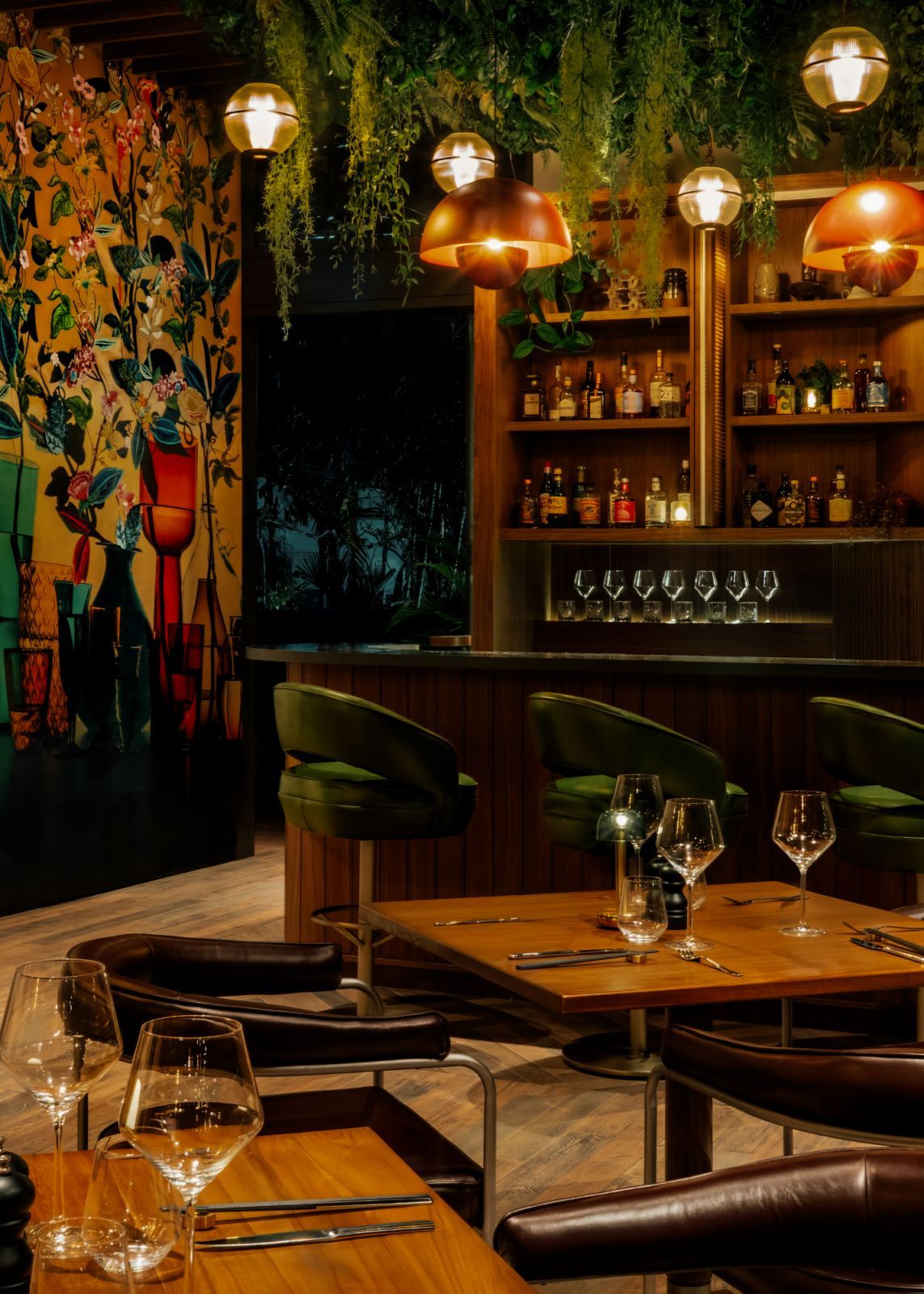 Intimate dining at The Standard Singapore’s Kaya featuring copper-toned mid-century modern pendant lighting, tropical mural art, and sleek wooden bar counter—showcasing the hotel's distinctive design narrative (Photo: The Standard Singapore)