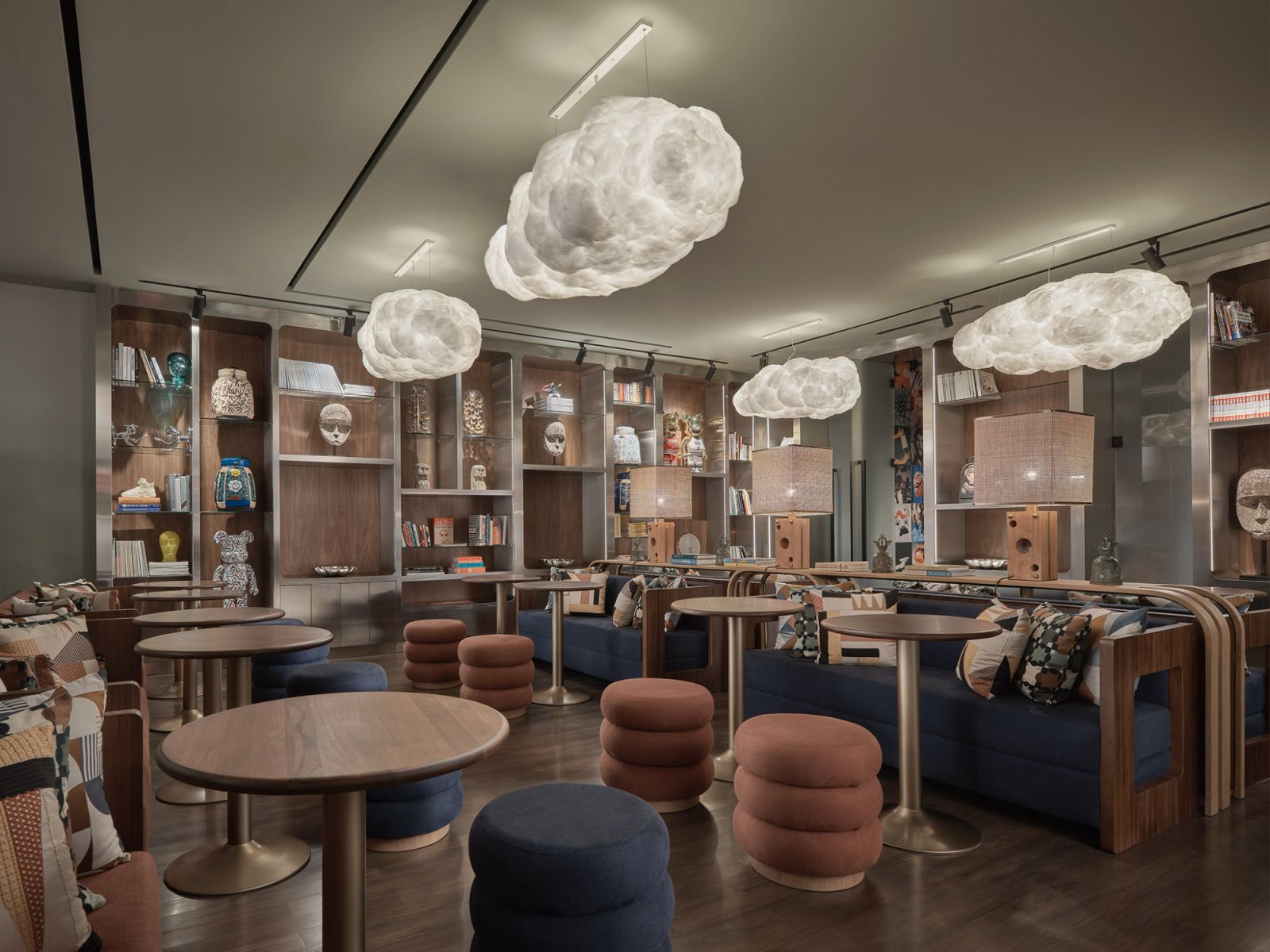 Library lounge at Public House Hotel Bangkok with cloud-shaped pendant lights, curated display shelves, and circular seating elements that create intimate gathering spaces within the property's modernist framework (Photo: Public House Hotel Bangkok)