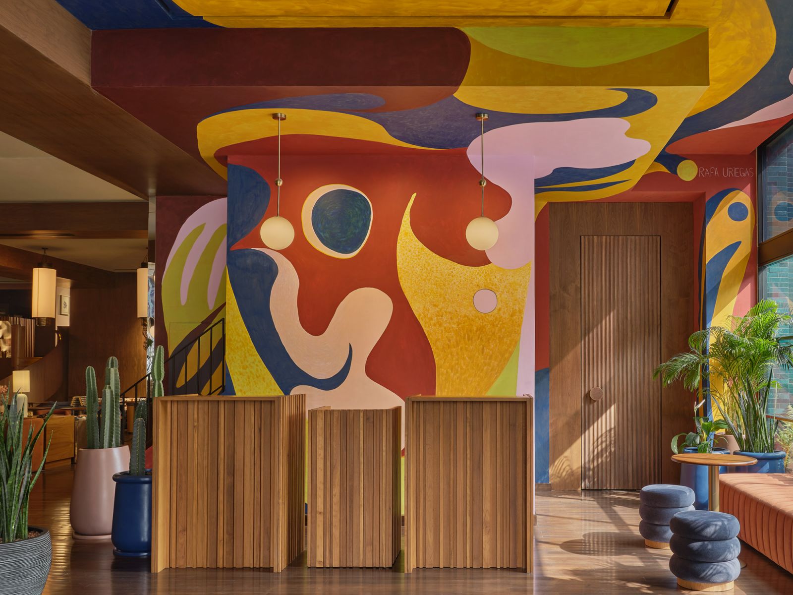 A vibrant mural by Rafael Uriegas is complemented by ribbed wooden partitions, creating a playful interpretation of mid-century modernism with contemporary artistic expression  (Photo: Public House Hotel Bangkok)