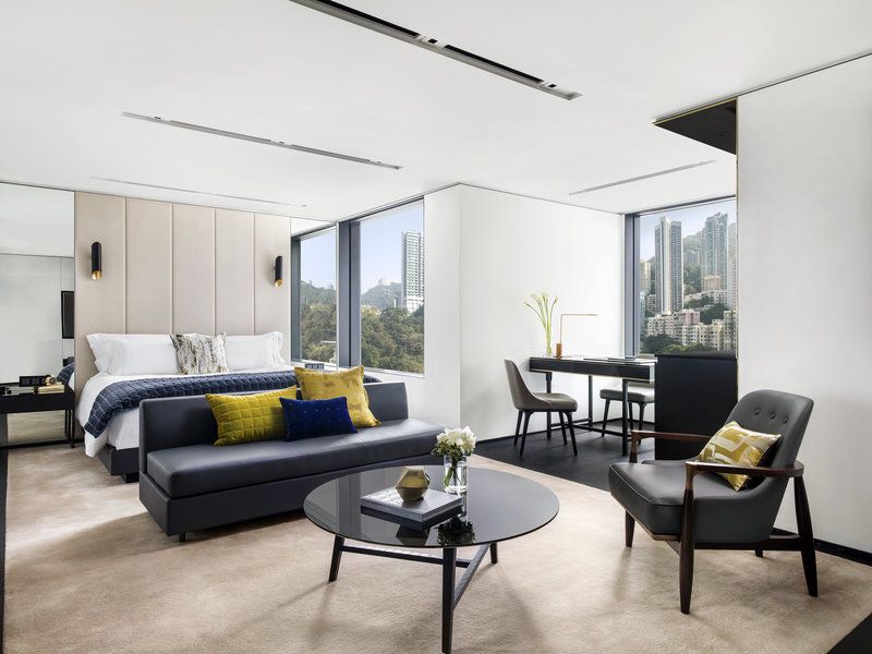 Guest suite at The Murray Hong Kong showcasing Foster + Partners’ elegant renovation with mid-century modern furnishings, panoramic city views, and sophisticated color palette of gray, blue and mustard (Photo: The Murray)