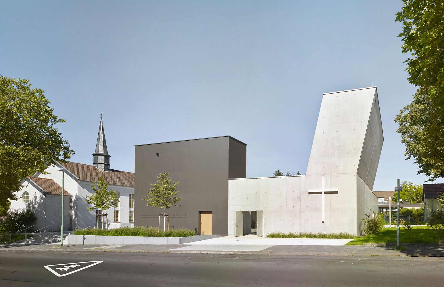 Traditional St. Luke Church (left) connected to the new grey parish hall and white concrete "outer church" (right), creating a west-to-east architectural timeline (Photo: Meixner Schlüter Wendt)