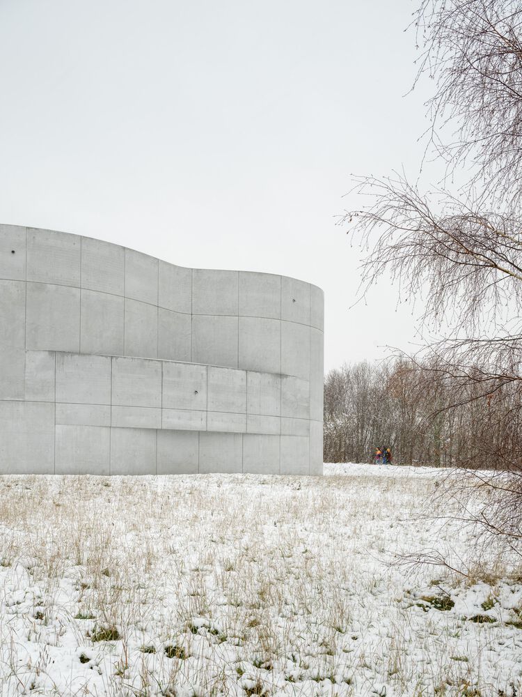 Side view of Trekroner Church's flowing concrete exterior demonstrating the building's sculptural quality and how it harmonises with the natural environment (Photo: Rørbæk og Møller Arkitekter)