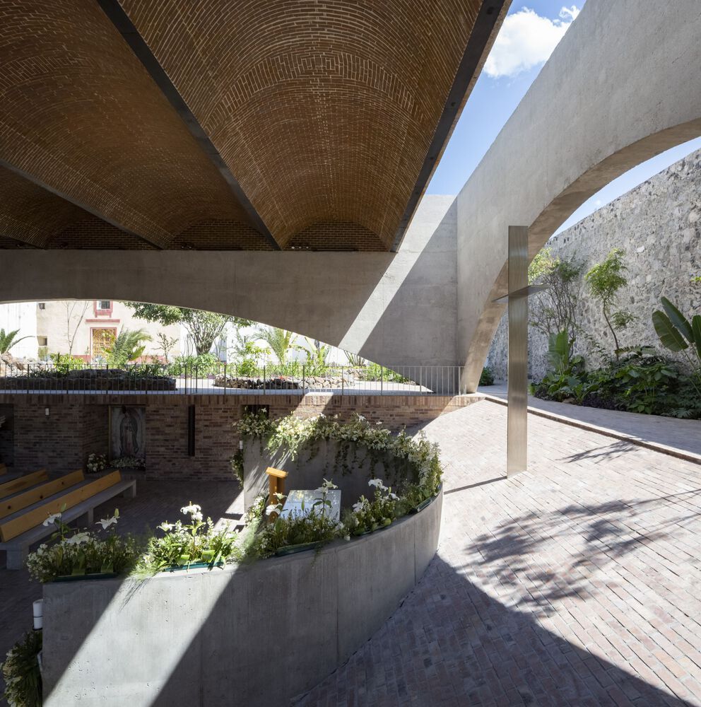 View of the transitional space between sanctuary levels, showcasing the brick vaults and concrete structure, with planters integrating nature into the worship space (Photo: Dellekamp Schleich + AGENdA Agencia de Arquitectura)