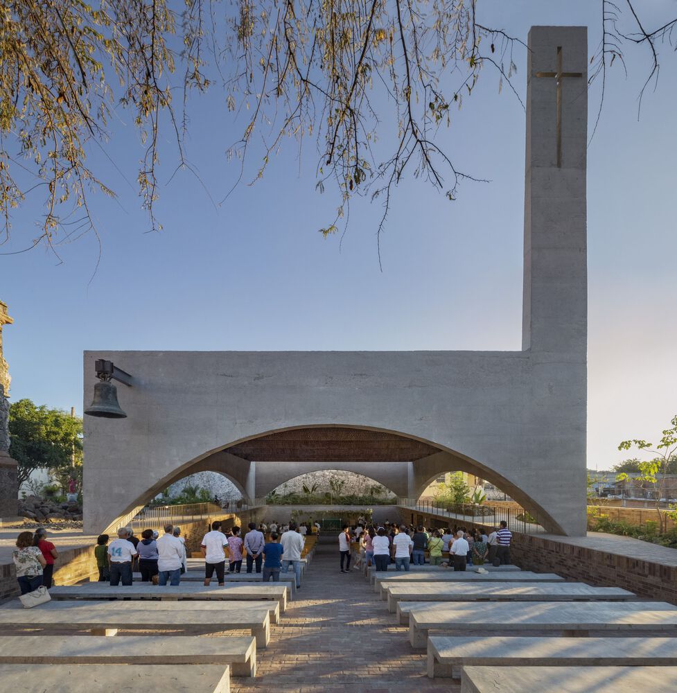 Exterior perspective showing worshippers gathered beneath the concrete arches, demonstrating how the design allows for flexible use of space during services (Photo: Dellekamp Schleich + AGENdA Agencia de Arquitectura)