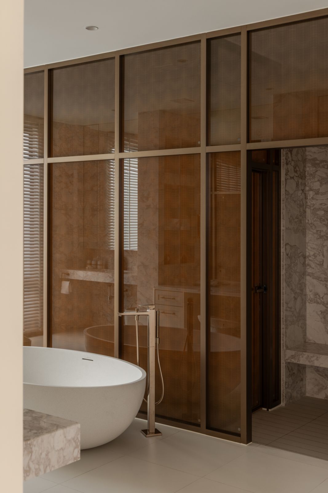 Luxurious master bathroom featuring a freestanding soaking tub, paired with dual fixtures including separate toilets, basins and showers, all finished in premium materials