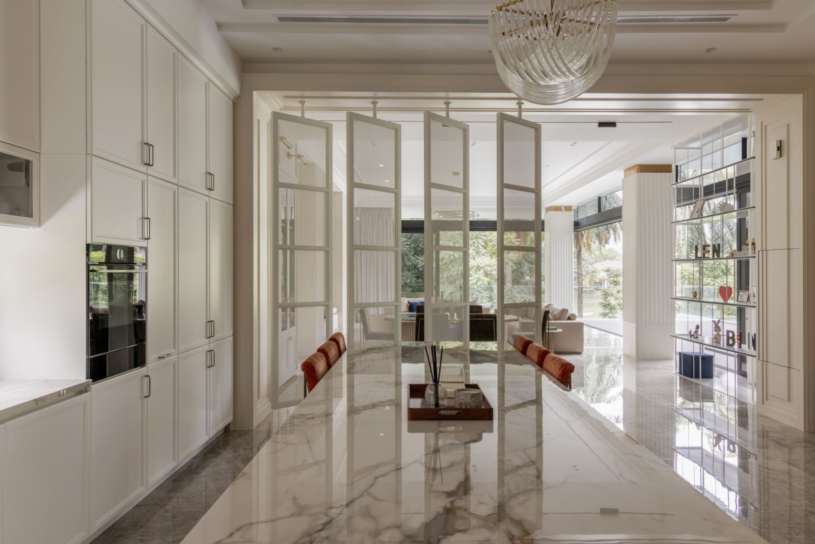 Four rotatable pivot doors separate cooking spaces from formal areas, allowing flexible privacy while maintaining the home's open flow
