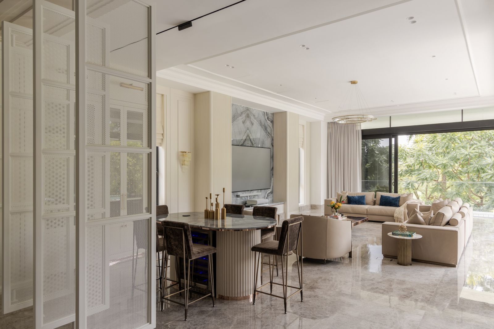 Sophisticated living area with marble flooring, elegant architectural elements and circular lighting fixtures overlooking the outdoor pool.