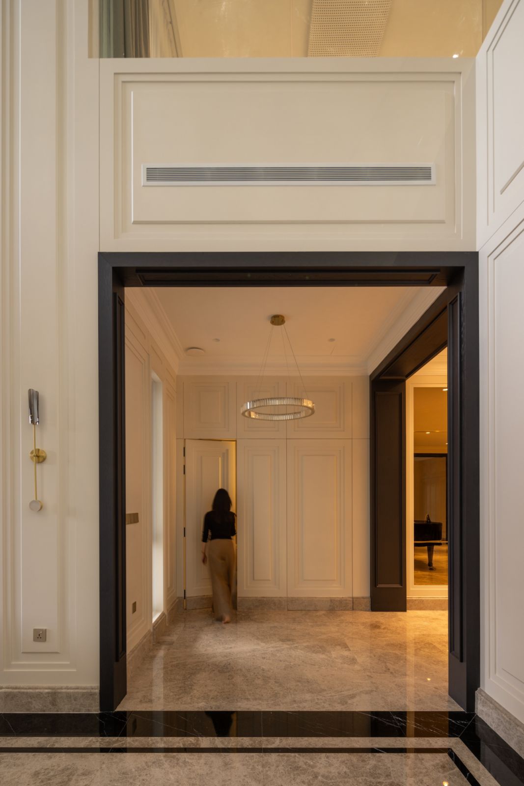 Double-height entrance foyer with elegant wainscoting, a circular chandelier, and marble flooring, exemplifying the home’s classic-modern fusion