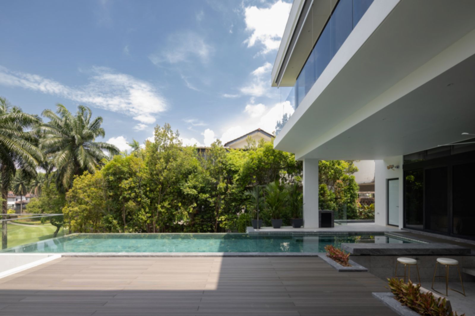 Luxurious outdoor pool featuring distinctive Sukabumi tiles that complement the surrounding greenery of the golf park, with a sunken deck designed for intimate family gatherings