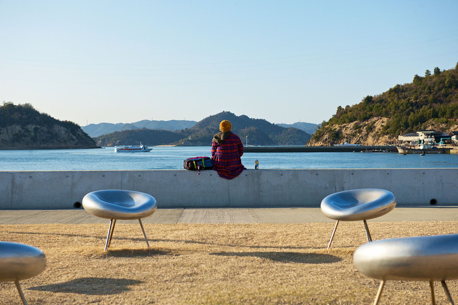 Naoshima, Japan-02 20 2015:Single person sitting by the water admiring the seascape of the Naoshima island in Japan. Naoshima is an island town administratively part of Kagawa District, located in the Seto Inland Sea.The administrative town is made up of 27 islands, of which Naoshima Island is the largest.Naoshima Island is known for its many contemporary art museums.