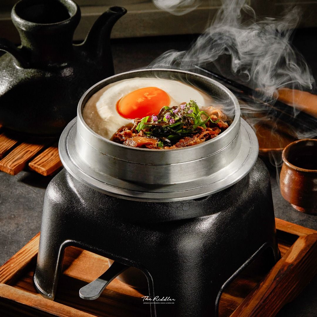 เมนูซิกเนเจอร์อย่าง Kamameshi ข้าวอบหม้อดินกับเนื้อและลิ้นวัว เสิร์ฟพร้อมหัวไชเท้ารมควัน และโกโบ เสริมด้วยโฟมชีส และไข่แดงจาก The Riddler (ภาพ: Instagram / @theriddlerbangkok)