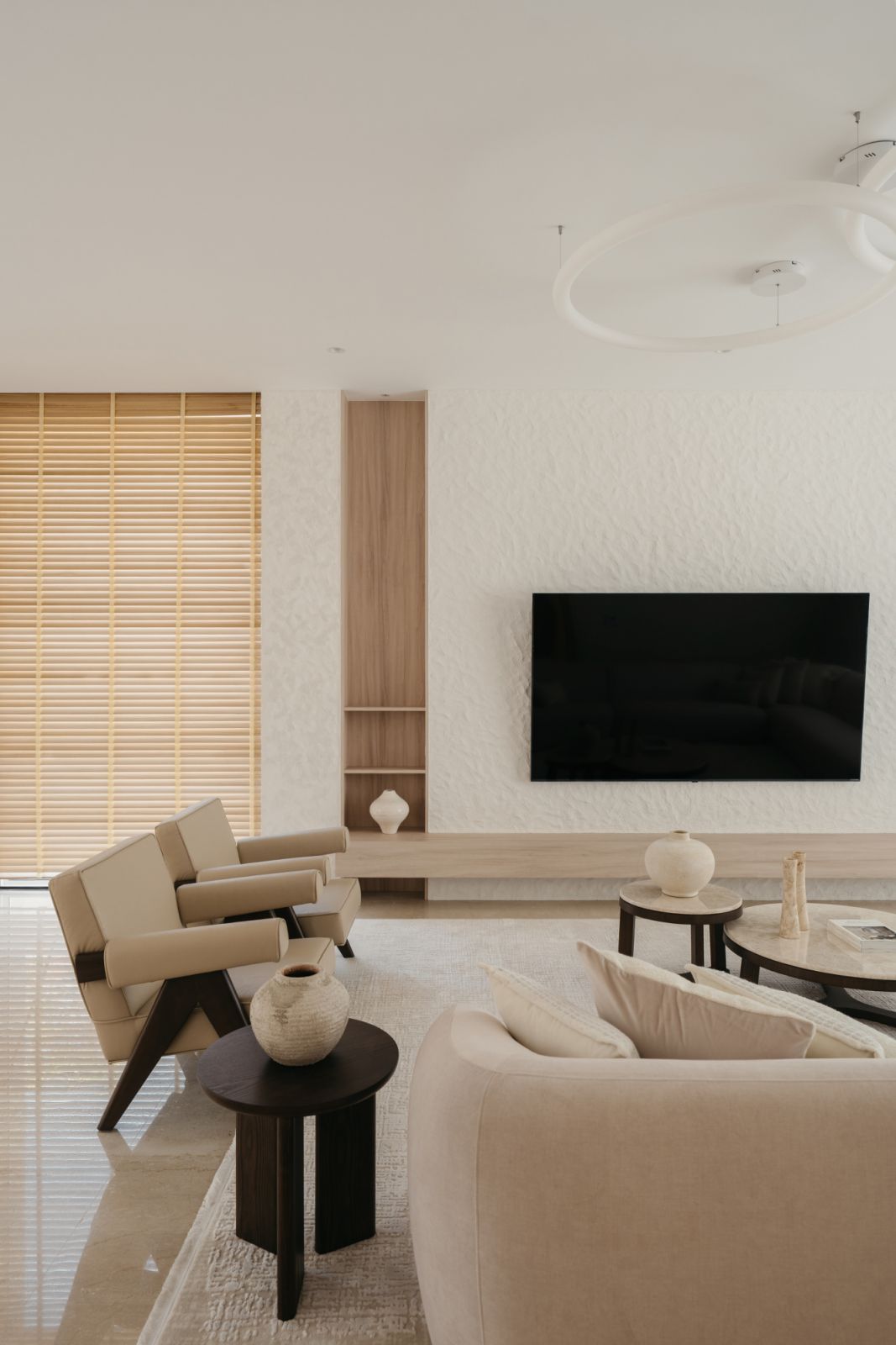 A serene Penang living room featuring a textured wall, wooden accents and a minimalist furniture arrangement.