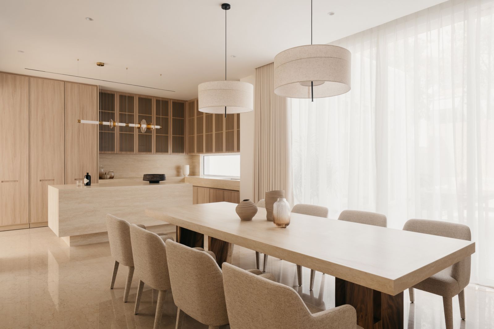 Open-concept kitchen and dining area with limestone island, fabric pendant lighting and Japanese-inspired slatted cabinetry