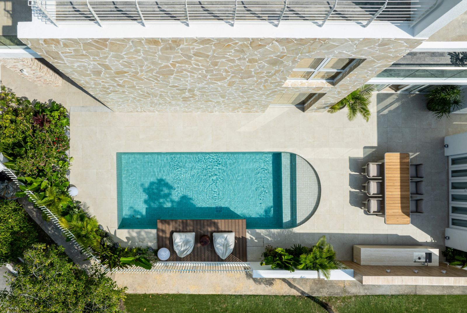 Overhead view of 30-foot mosaic-tiled swimming pool with German stone feature wall and tropical garden landscaping.