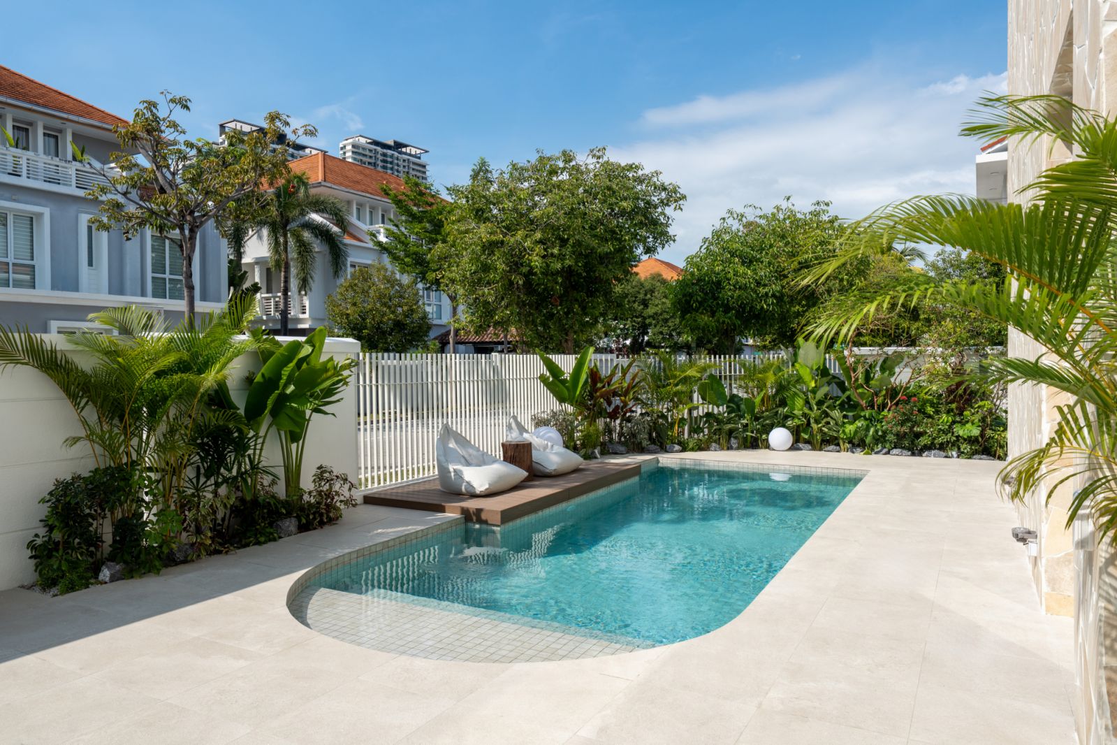 Outdoor living perspective showcasing curved pool edge and strategic plantings that create privacy within gated community