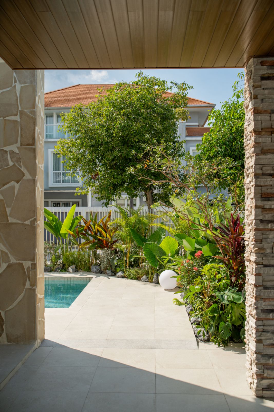 Framed courtyard view revealing lush tropical landscaping and intimate pool sanctuary at Penang waterfront bungalow.