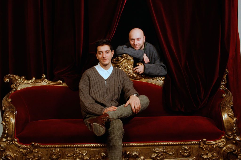 Portrait of Italian fashion designers Domenico Dolce and Stefano Gabbana sitting on a red velvet sofa. 1980s (Photo by Mondadori via Getty Images)