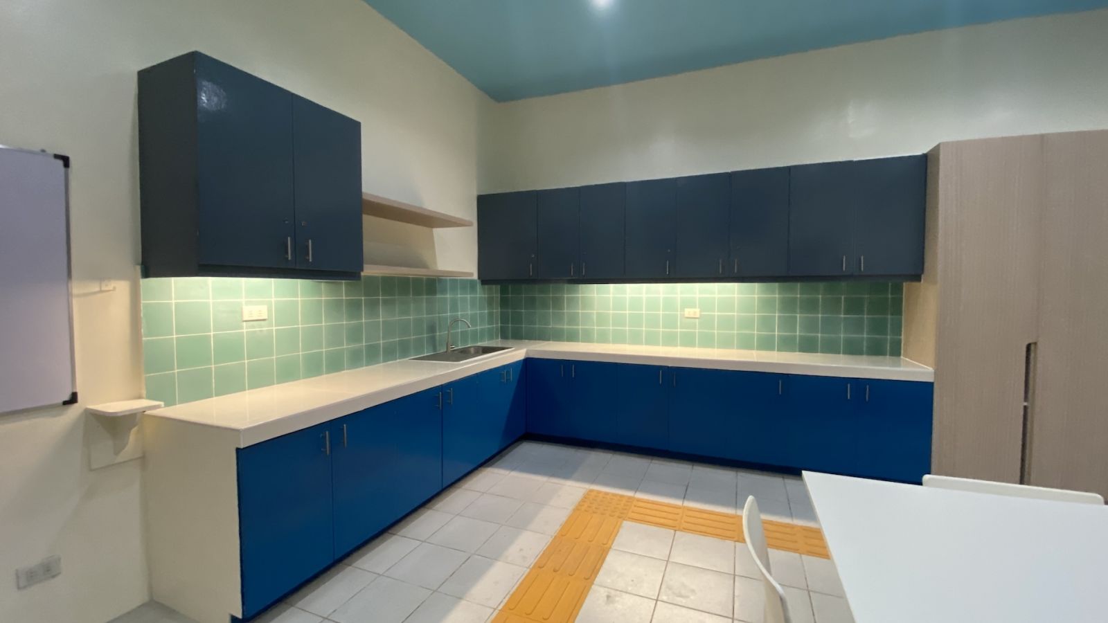 Following the consistency of the interior renovation, the updated girls' dormitory kitchen area features new backsplash tiles, freshly painted cabinets, and enhanced lighting at Hospicio De San Jose