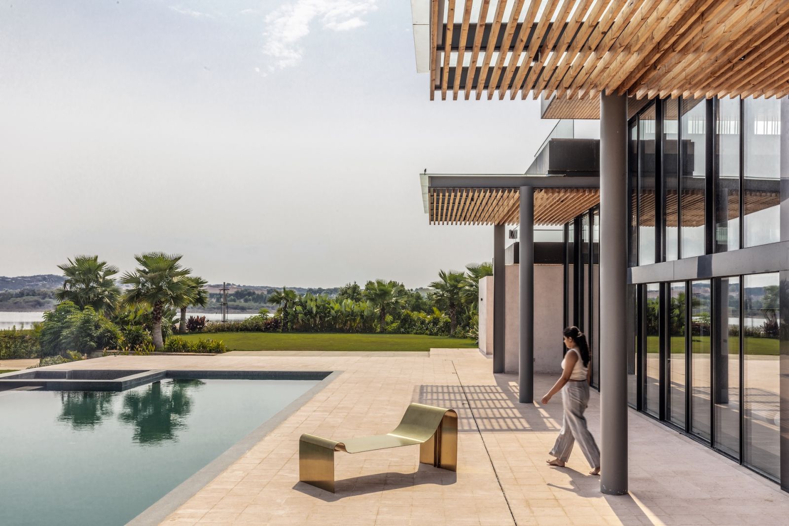 The outdoor terrace and swimming pool at a Hyderabad, India home, with views of the Himayat Sagar Lake