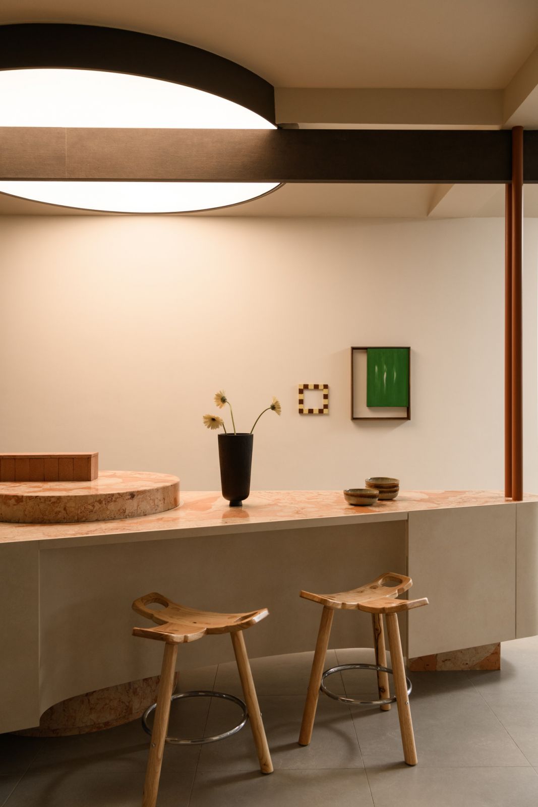 The curved kitchen island with its distinctive pink marble countertop embodies the home's balance of functionality and sculptural form