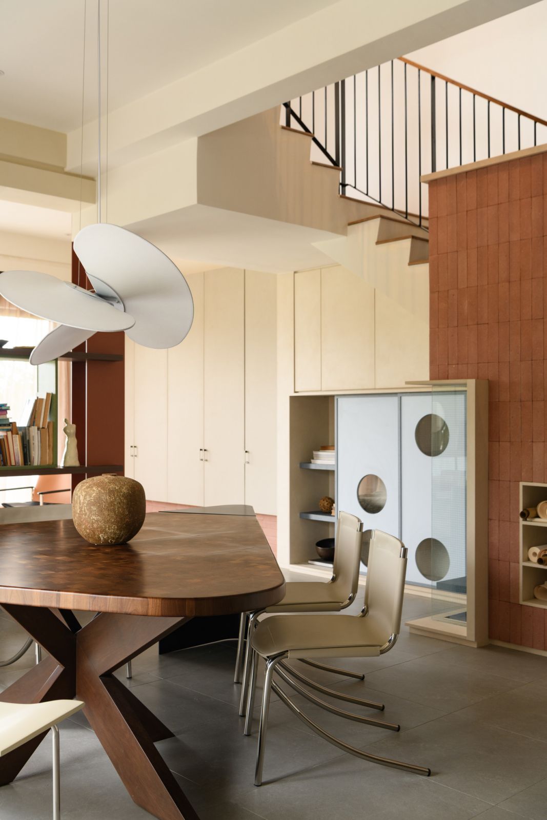 The dining area features a statement timber table with sculptural base, complemented by contemporary seating