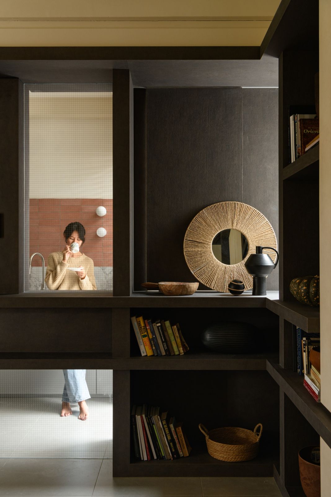 The floating bookshelf divider creates visual separation between living zones while maintaining spatial flow
