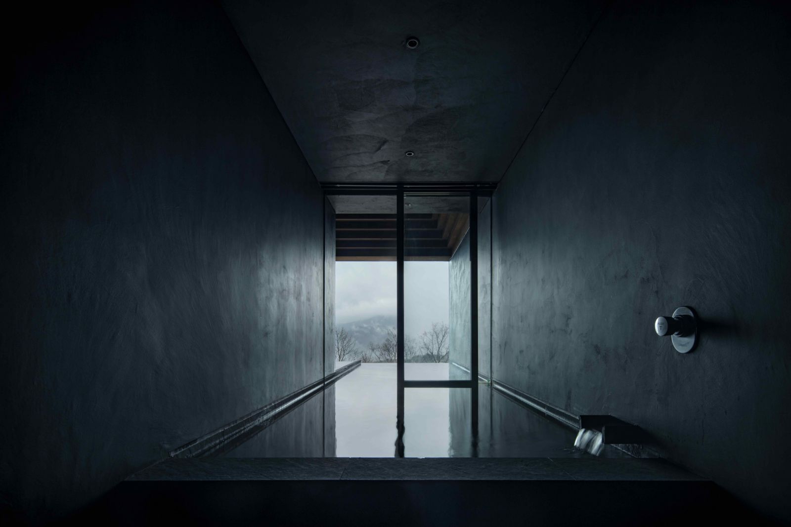 The hot spring bath framed by black architectural walls
