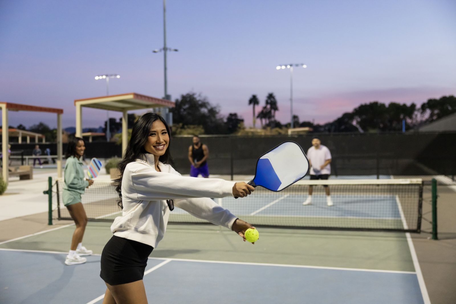 A diverse group playing pickleball at night.